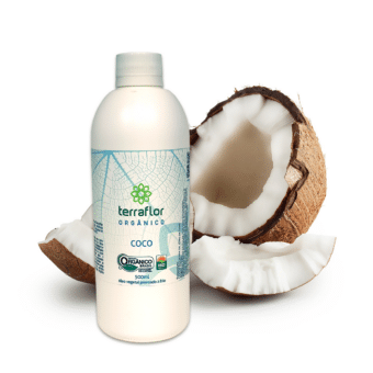 Frasco do óleo vegetal de coco orgânico 500ml com coco aberto ao fundo.